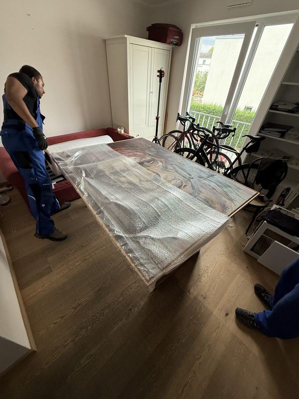 Auf einem Tisch liegt ein großes gerahmtes Bild, komplett in Luftpolsterfolie eingeschlagen