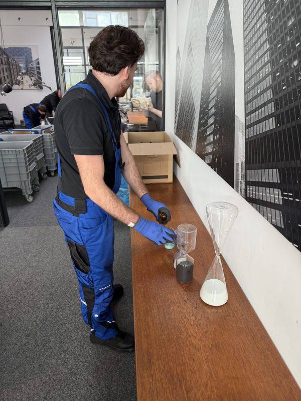 Mit Handschuhen legt ein Mitarbeiter Glas für Glas in einen Umzugskarton