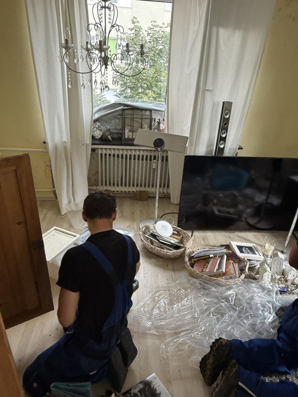 Auf dem Boden kniend sortiert ein Mitarbeiter Hausrat aus Kisten und Körben