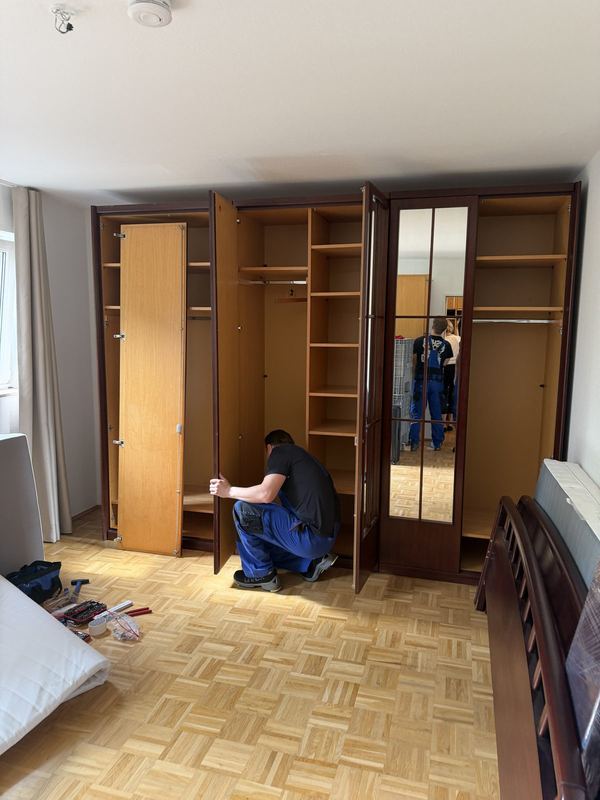 In einem Schlafzimmer justiert ein Mitarbeiter die Türen an einem Kleiderschrank mit mehreren Türen