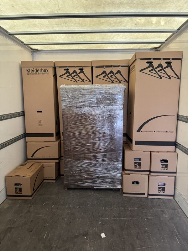 Blick in einen Laderaum mit einer Reihe Kleiderboxen, mittig steht ein folierter Schrank
