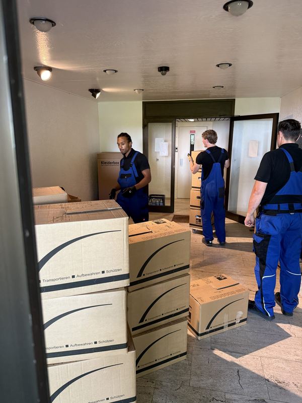 Im Flur werden Umzugskartons von mehreren Mitarbeitern zum Abtransport bereitgestellt