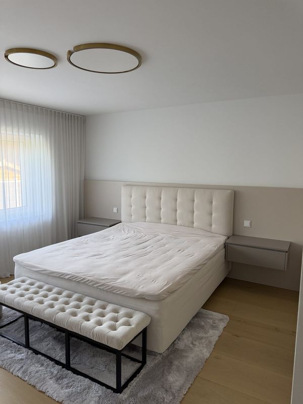 Helles Schlafzimmer mit fertig aufgebautem Boxspringbett und einer Sitzbank am Fußende