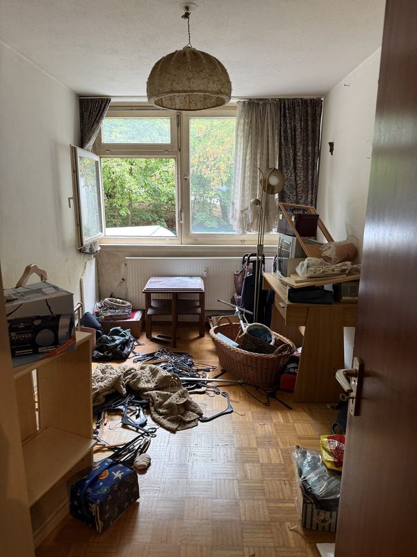 Zimmer vor dem Ausräumen, auf dem Boden verteilt liegen Kleiderbügel, Körbe und Kartons